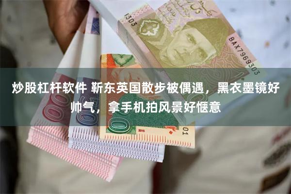 炒股杠杆软件 靳东英国散步被偶遇，黑衣墨镜好帅气，拿手机拍风景好惬意